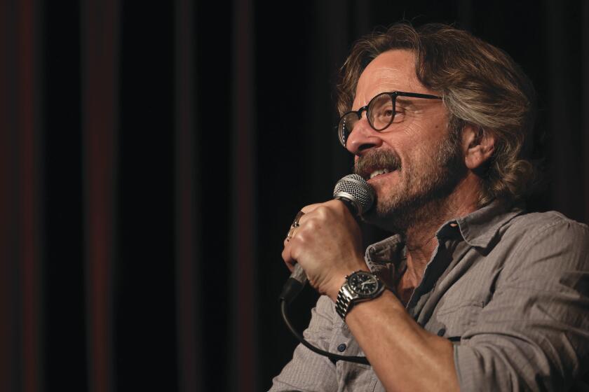 Comic Marc Maron holds a microphone