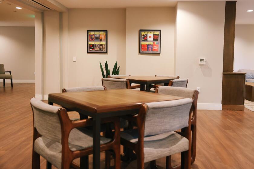 A room with hardwood floors furnished with tables, chairs and framed posters on the wall