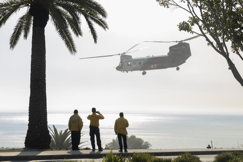 MALIBU, CA - DECEMBER 10: An Orange County fire helicopter lifts off after picking up water from a pond at Pepperdine University while fighting the Franklin fire in Malibu, CA on Tuesday, Dec. 10, 2024. (Myung J. Chun / Los Angeles Times)