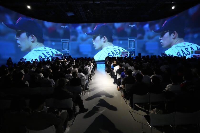 People watch pitcher Roki Sasaki of Japan on a live stream of a World Baseball Classic (WBC) semifinal between Japan and Mexico being played at LoanDepot Park in Miami, during a public viewing event Tuesday, March 21, 2023, in Tokyo. (AP Photo/Eugene Hoshiko)