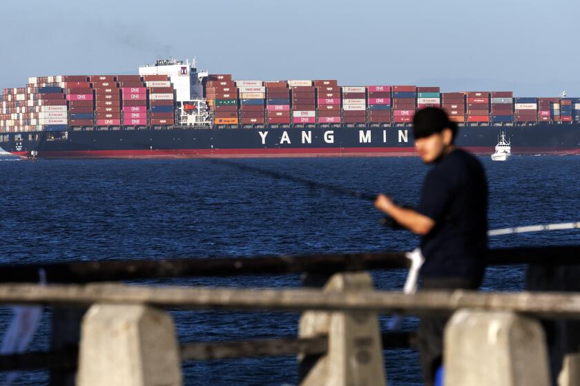 SAN PEDRO, CA - JUNE 25, 2024: A cargo ship leaves the Port of Los Angeles as a fisherman waits for his catch off the Cabrillo Beach Pier on June 25, 2024 in San Pedro, California.(Gina Ferazzi / Los Angeles Times)