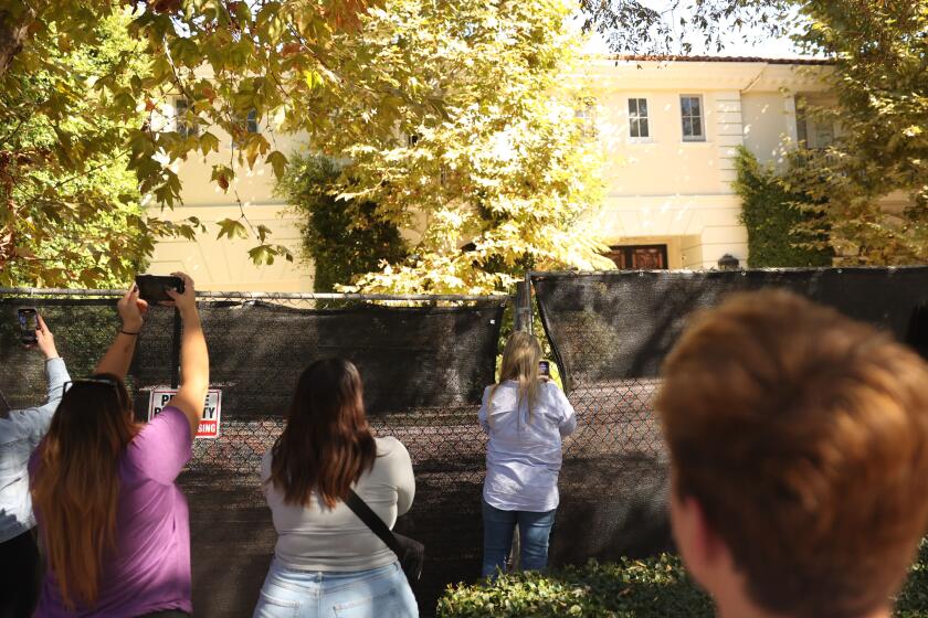 Beverly Hills, CA - October 23: Visitors takes photos of the Menendez brothers' former mansion on Wednesday, Oct. 23, 2024 in Beverly Hills, CA. (Michael Blackshire / Los Angeles Times)