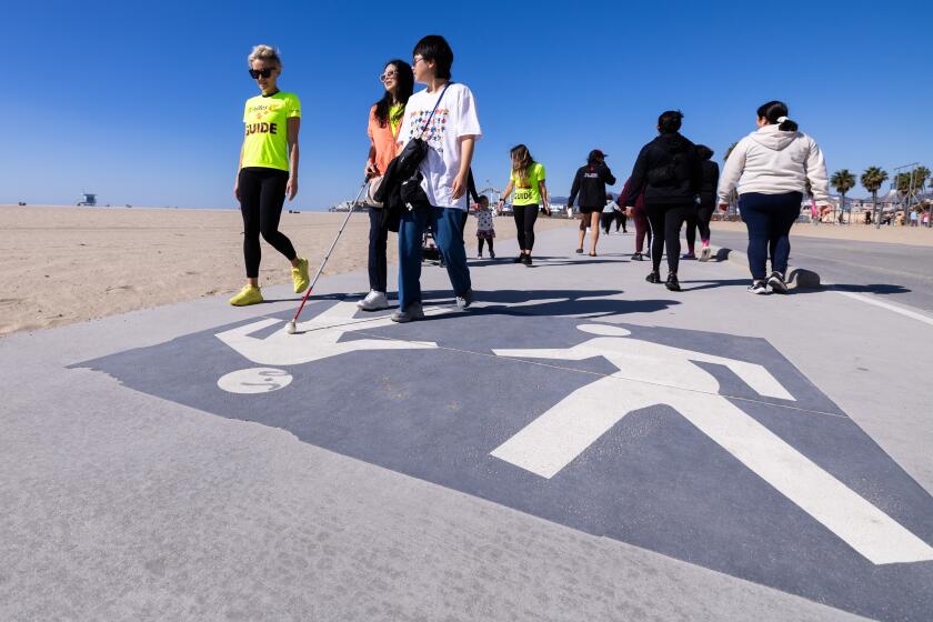 Santa Monica, CA - November 03: Achilles Los Angeles guide Heather Cox, left, walks with Hsiu-ling Chang, center and Chae Won, right, during nonprofit walking/running group's monthly meetup on Sunday, Nov. 3, 2024 in Santa Monica, CA. The organization pairs people with disabilities with able-bodied people to walk in groups. (Brian van der Brug / Los Angeles Times)