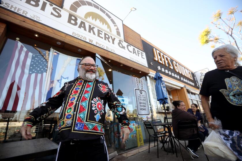 LOS ANGELES, CA - NOVEMBER 14, 2024 - - Shlomo Walt, 49, left, the unofficial "Mayor of Pico" greets a visitor at Bibi's Bakery & Cafe Scenes in the primarily Jewish neighborhood of Pico Robertson in Los Angeles on November 14, 2024. (Genaro Molina/Los Angeles Times)