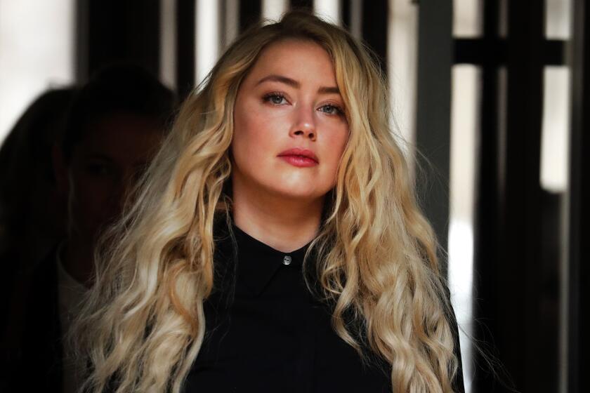 Amber Heard, in a black top and curly blond hair, arrives at a London court amid her 2020 trial with ex-husband Johnny Depp 