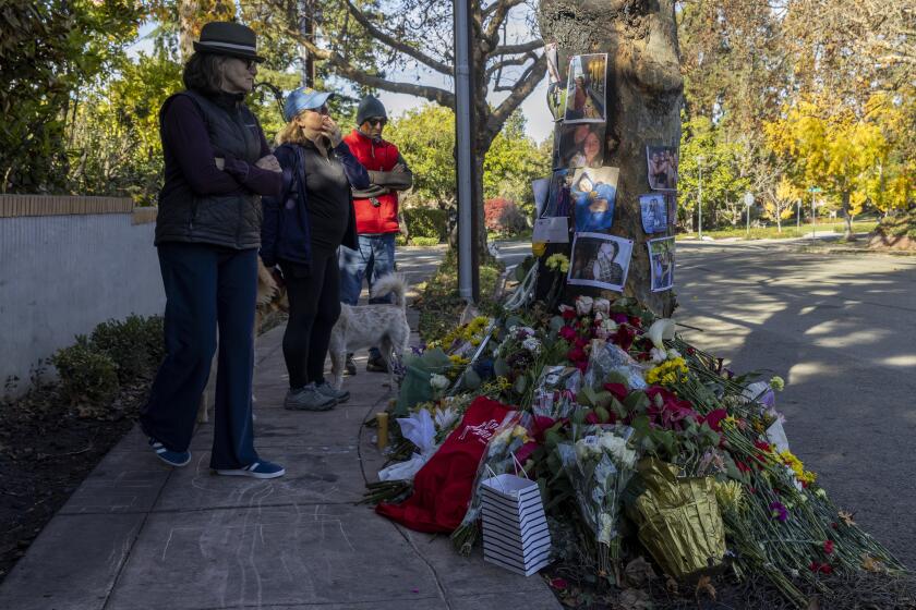 People visit a memorial displayed for victims of a Tesla Cybertruck crash in Piedmont, Calif., on Friday, Nov. 29, 2024. (Santiago Mejia/San Francisco Chronicle via AP)