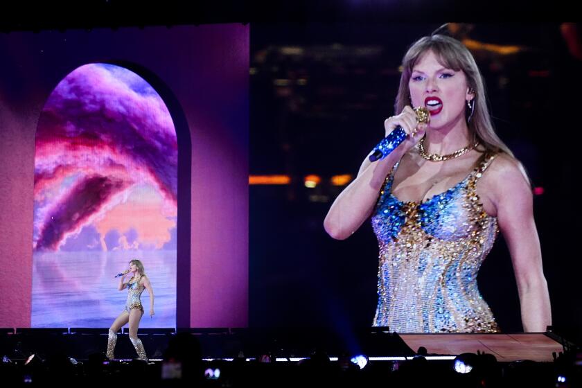 Taylor Swift performs during "The Eras Tour" on as a larger image of her is projected on a screen behind her